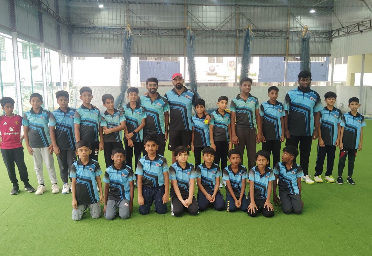 A full junior squad in Elite kit lined up across the indoor turf at the Chennai academy in Medavakkam.